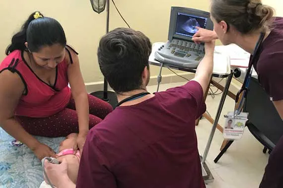 Two students examine an infant with an ultrasound exam in Chiapas.