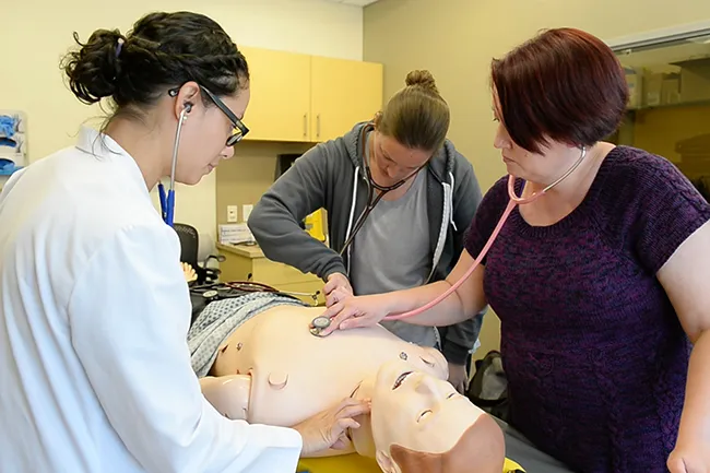 Students practice giving medical care to a dummy