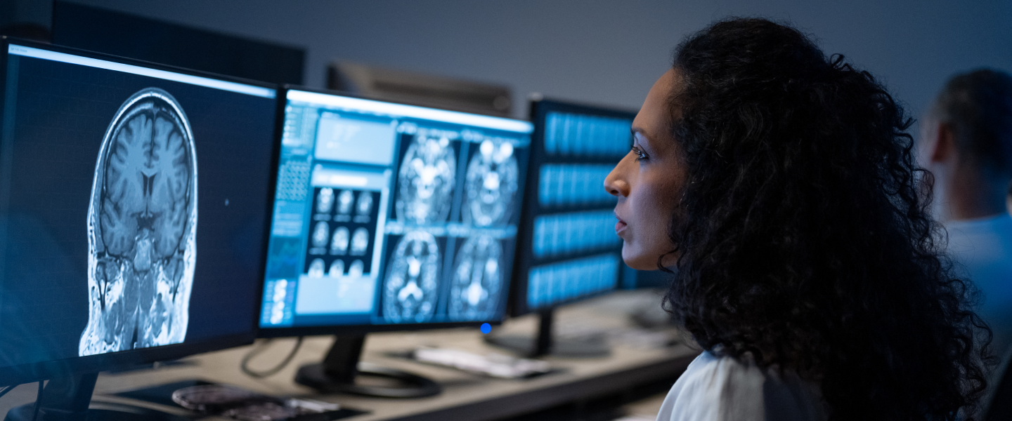 A female physician analyzing a brain scan over a laptop.