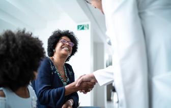 Female doctor welcoming and greeting mother and daughter at hospital